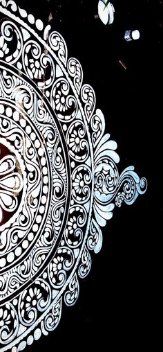 an intricate design on the side of a black wall with white circles and swirls