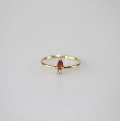 A timeless blend of elegance and versatility. Crafted with a stunning pear-shaped garnet gemstone and cute white little AAA cubic zircon. Wear it solo for understated chic or stack it up for a personalized statement. Embrace timeless beauty with our Garnet Pear Stacker Ring! 18k gold plated Stainless steel based Waterproof and tarnish free Available in US size 6-8 Ring sizing chart Elegant Pear-shaped Red Rings, Ring Sizing Chart, Stacker Rings, Garnet Gemstone, Sizing Chart, Pear Shaped, Timeless Beauty, Garnet, Pear