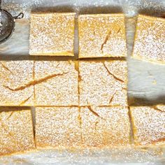 several pieces of cake sitting on top of a table next to a teapot and spoon