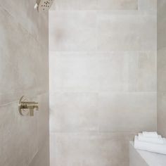 a bathroom with a shower head and white tile walls