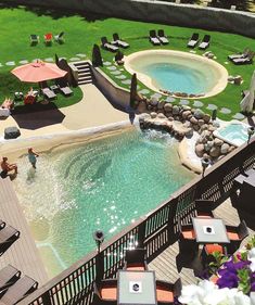 an aerial view of a pool with chairs and umbrellas in the grass next to it