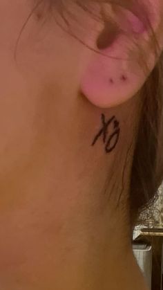 a woman with a small tattoo on her neck and behind her ear that reads'xo '