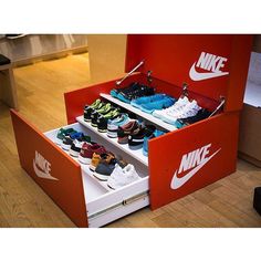 an open shoe box with several pairs of nike shoes in it on the wooden floor