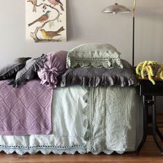 a bed sitting in a bedroom next to a lamp and pictures on the wall above it