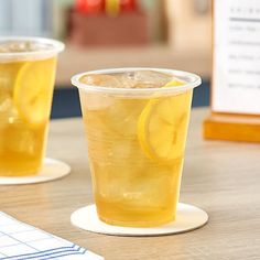 two cups filled with lemonade sitting on top of a table