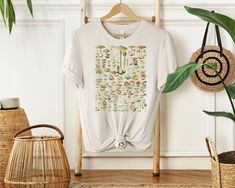 a t - shirt hanging on a clothes rack next to a potted plant and wicker basket