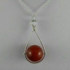 a pendant with a red stone hanging from it's side on a silver chain