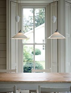 three lights hanging from the ceiling over a table in front of a window with an open door