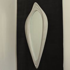 a mirror hanging on the wall in front of a black and white background with an abstract shape