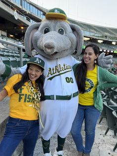 two women pose with a mascot at a baseball game