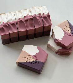 four different types of chocolates on a white counter top, one is pink and the other is purple