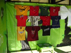 there are many t - shirts hanging on the clothesline in front of a green wall