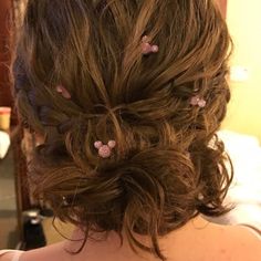 the back of a woman's head with pink flowers in her hair and curls