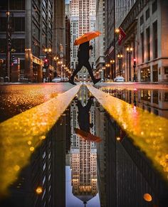 a person holding an umbrella walking across a street in the middle of a city at night