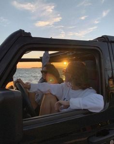 two people sitting in the passenger seat of a truck with the sun setting behind them