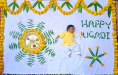 a young child laying in front of a flag with the words happy ugadi written on it