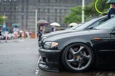 a black car parked in the rain with an umbrella over its head