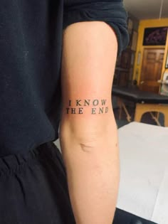 a person with a tattoo on their arm that says i know the end, in black ink