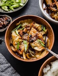 two bowls filled with food and rice on top of a black countertop next to other dishes