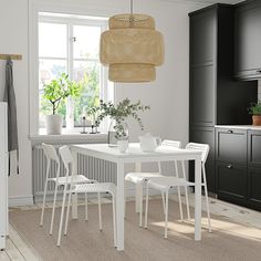 a white table and chairs in a room with black cupboards on either side of the window