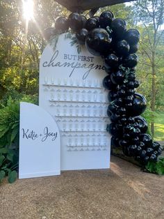 a sign that says but first champagne next to some balloons in the shape of wine bottles