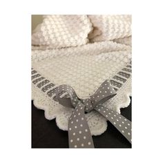 a white crocheted blanket with grey polka dots on it and a gray ribbon around the edge