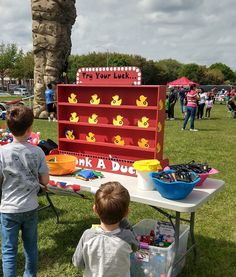 two young boys standing in front of a table with toys on it and an advertisement for duck a dog