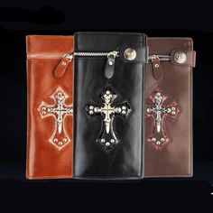 three different colored leather wallets with crosses on the front and back, one in brown, one in black