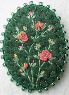 a green brooch with pink flowers on it