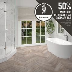 a bathroom with wood flooring and white tub next to windows that have sliding glass doors