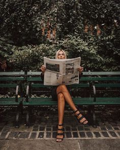 a woman sitting on a bench reading a newspaper