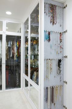 a closet filled with lots of necklaces and bracelets hanging on the wall next to glass doors