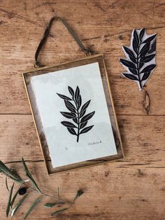 some leaves are sitting on a wooden table next to a paper cutout and scissors