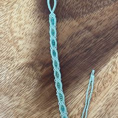 a close up of a piece of string on a wooden surface with scissors and thread