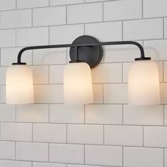 three light bathroom fixture with white glass shades and black metal frame on brick wall background