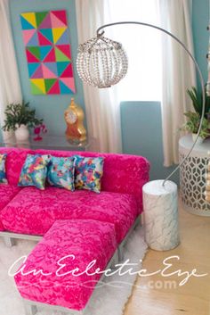 a living room with pink couches and colorful pillows on the floor in front of a large window