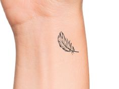 a small feather tattoo on the wrist