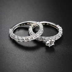 two diamond wedding rings on a black surface