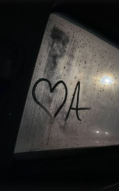 the window is covered with raindrops and has graffiti on it that says 2a