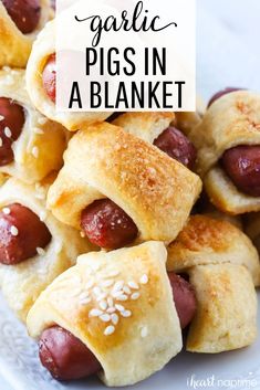 a white plate topped with pigs in a blanket filled with hotdogs and sesame seeds