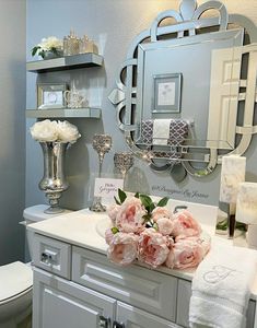 a bathroom vanity with flowers on it and a mirror above the sink, along with other items