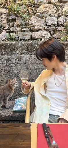 a woman holding a wine glass next to a cat