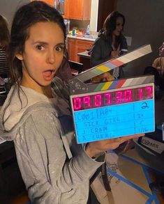 a woman holding up a clap board with the time on it