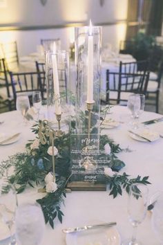 an elegant table setting with candles and greenery