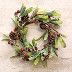 a christmas wreath with pine cones and holly berries on a stone wall, ready to be hung