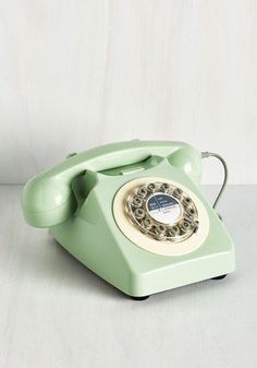 an old - fashioned green phone sits on a white surface