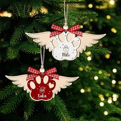 two ornaments hanging from a christmas tree decorated with red and white bows, paw prints