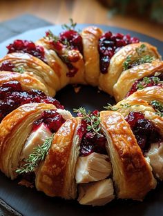 a turkey and cranberry bread wreath on a black platter with greenery