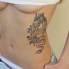 a woman with a dragon tattoo on her stomach is holding onto the side of her belly