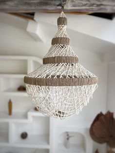 a white and brown hanging light fixture in a living room or dining room with open shelving